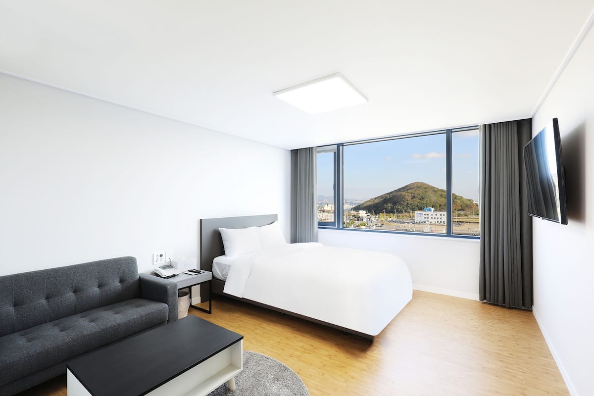 Una habitación de hotel moderna con cama, sofá, escritorio y televisión.