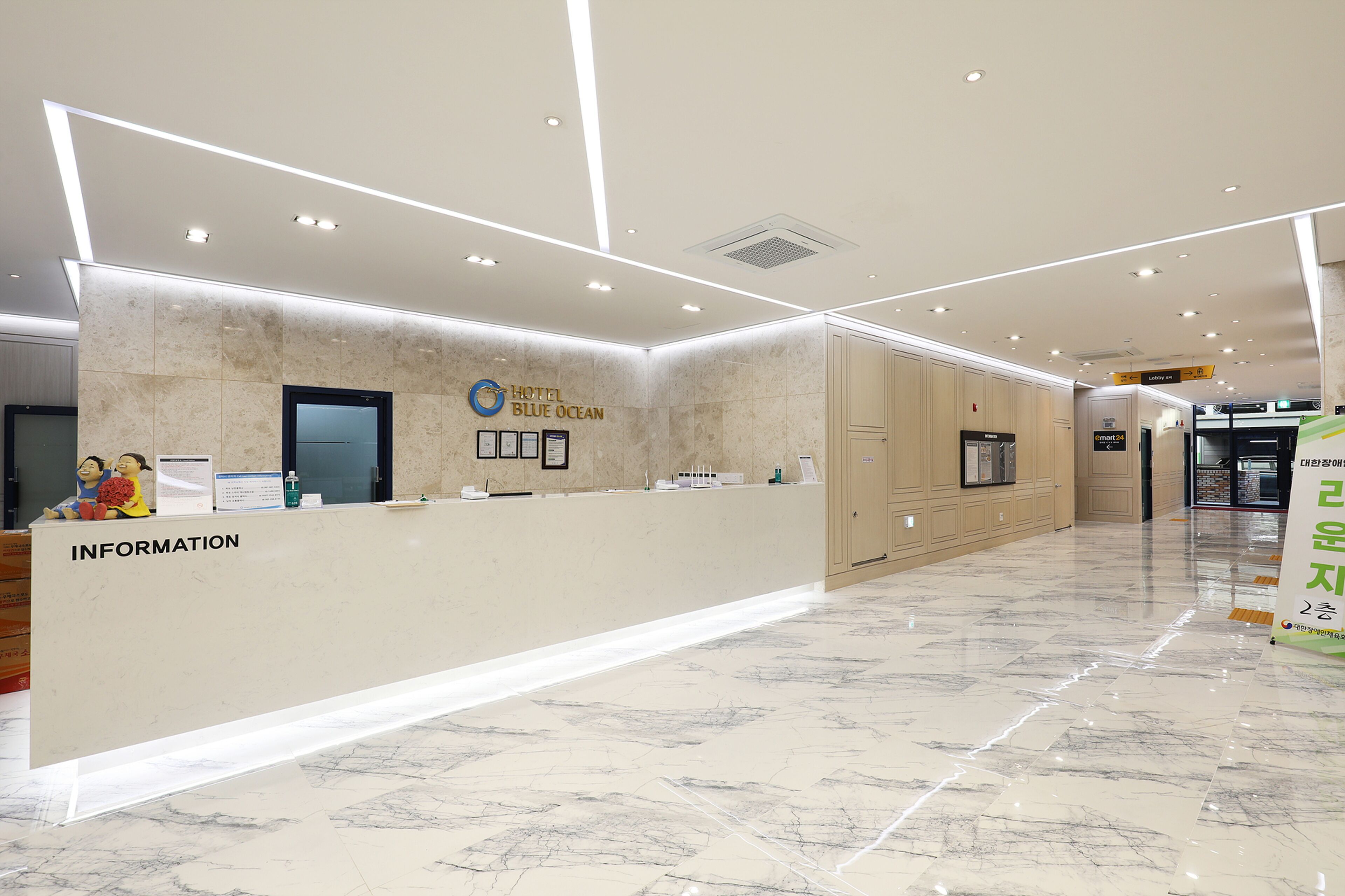 Zona de recepción de un hotel con piso de mármol, un mostrador de recepción identificado con 