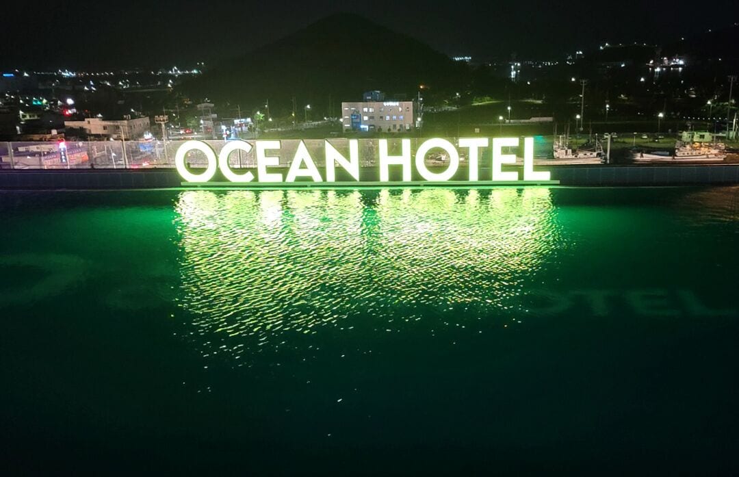El letrero del Hotel Ocean reflejado en el agua, con un paisaje urbano de fondo.