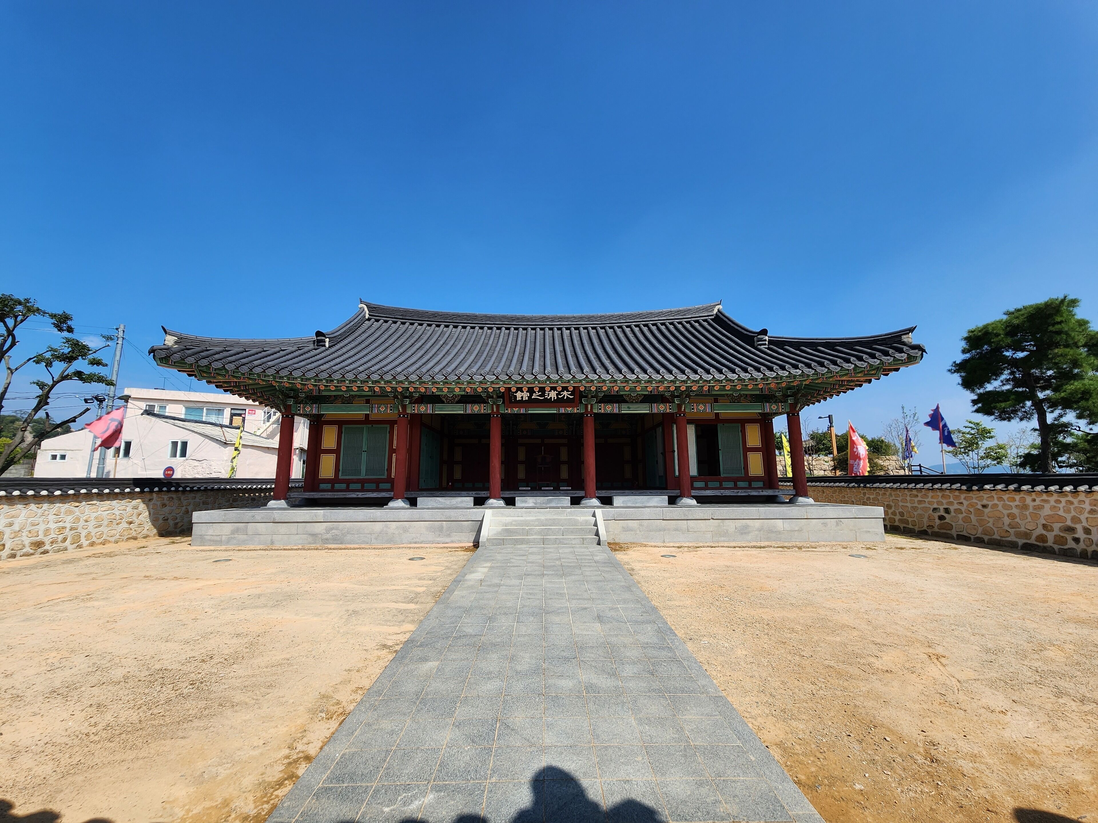Un edificio coreano tradicional con tejado de cerámica y un camino de piedra que lleva a la entrada.