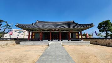 Un edificio coreano tradicional con tejado de cerámica y un camino de piedra que lleva a la entrada.
