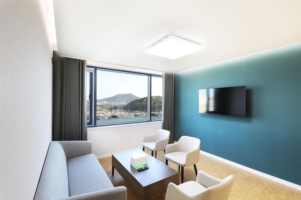 Habitación de hotel moderna con un ventanal grande, una televisión de pantalla plana, un sofá y una mesita de centro.