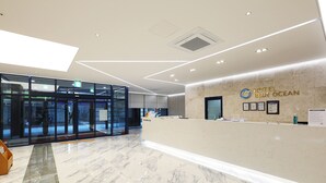 Una moderna zona de recepción de hotel con suelo de mármol, un mostrador de recepción y una puerta de entrada de cristal.