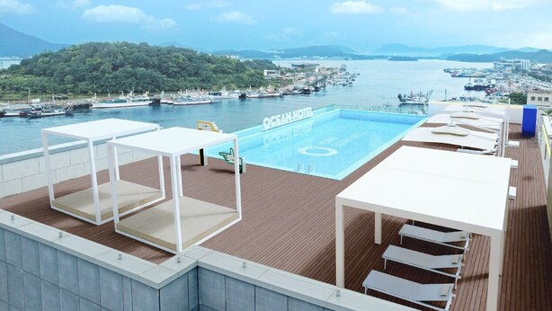 Una piscina en la azotea con vistas a un puerto deportivo y colinas al fondo.