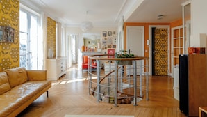 Un vaste espace de vie doté d’un plancher en bois, d’un canapé, d’un coin cuisine avec un îlot central et d’une table à manger.