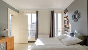 Une chambre à coucher avec un lit, une commode, un radiateur et une bibliothèque.