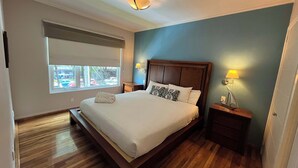 A neatly made bed with white linens, a wooden headboard, and two bedside lamps. - Arquimedes Deco - Colourful 1BR in Polanco (Mexico City)