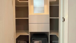 Um closet espaçoso com diversas prateleiras, um cofre embutido e uma pequena janela.