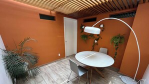 Une petite pièce moderne, avec une table ronde, un lampadaire blanc et une plante en pot.