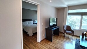 Moderni hotellihuone, jossa on sänky, työpöytä, tuoli ja suuri ikkuna.