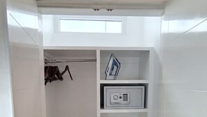 Ein kleiner begehbarer Kleiderschrank mit integriertem Bügeleisen, Kleiderstange und Mikrowelle.