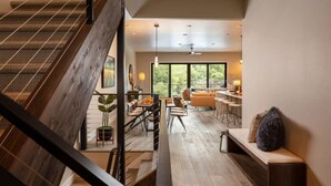 A modern interior with a wooden staircase, a dining area, and a seating area with a view of the outdoors. - Summit + Sky (Bozeman)