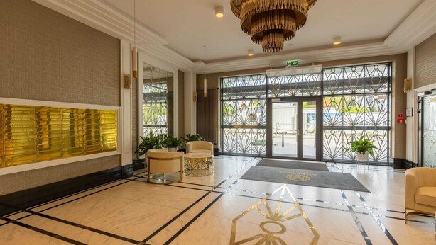 A spacious lobby with a marble floor, a large chandelier, and a reception desk. - Spacious Apartment with Balcony | Parking | Gym (Warszawa)