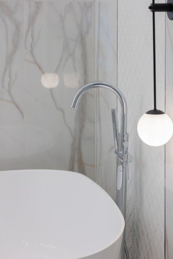 Un baño moderno con una bañera blanca, un grifo cromado y un revestimiento de pared texturizado.