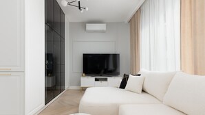 A modern living room with a large flat-screen TV, a white sofa, and a marble coffee table. - Spacious Apartment with Balcony | Parking | Gym (Warszawa)