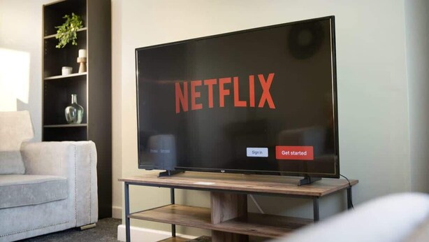 A flat-screen TV on a wooden stand with a Netflix logo and 'Sign in' and 'Get started' buttons. - Family two Bedroom Home Free Parking and Backyard (Howden-le-Wear)