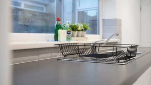 A kitchen with a dish rack, a window, and a plant on the windowsill. - Family two Bedroom Home Free Parking and Backyard (Howden-le-Wear)
