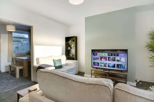 A modern living room with a sofa, a television, a small table, and a bookshelf.