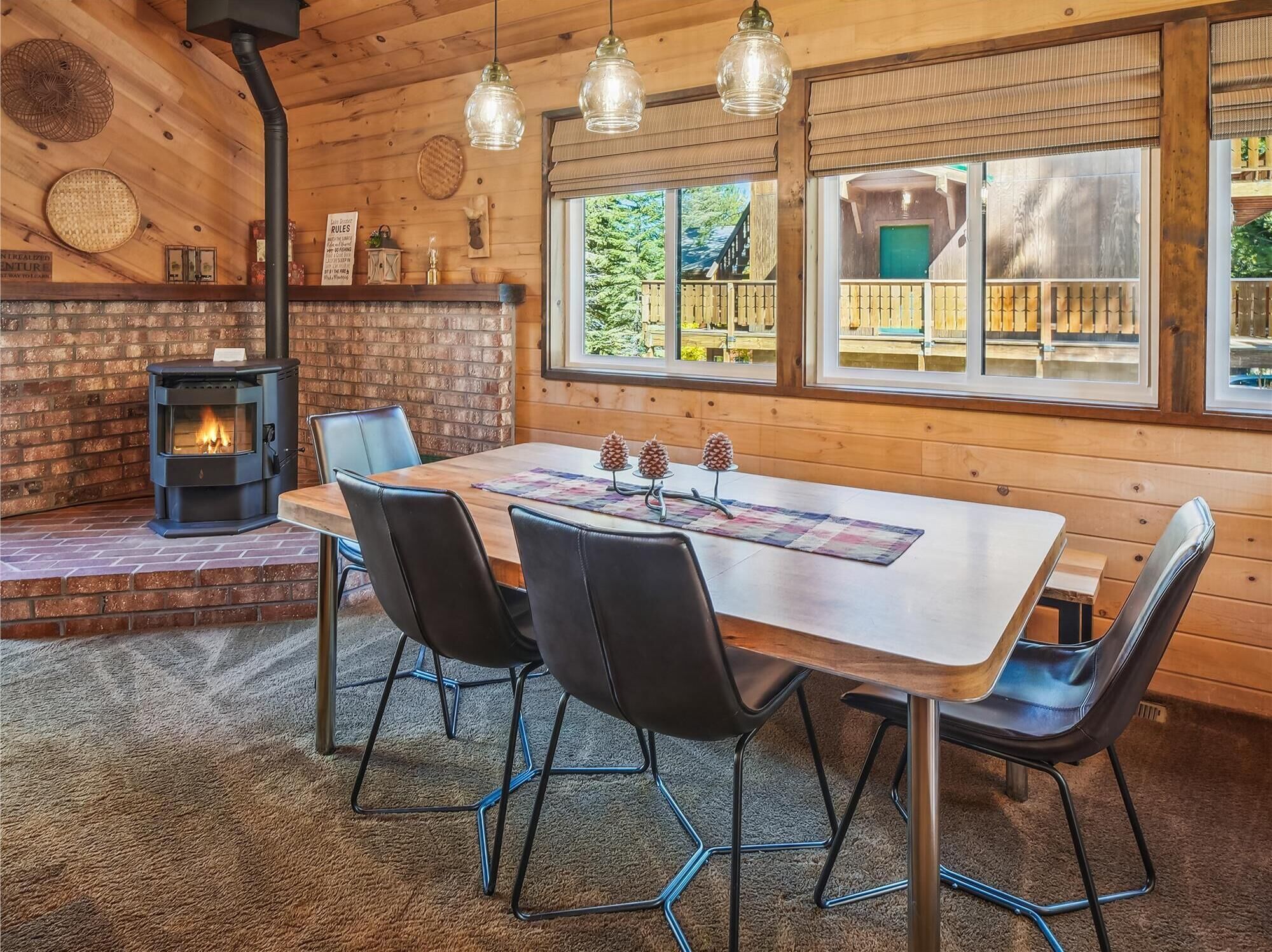 Interior acogedor de una cabaña con chimenea, paredes de madera y comedor con sillas y mesa.