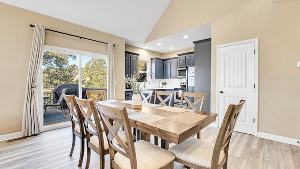 A modern kitchen with dark cabinets, a central island, and a dining area with wooden chairs and a table. - 5BR Retreat Sleeps 16 | Hot Tub, Game Room (Hollister)