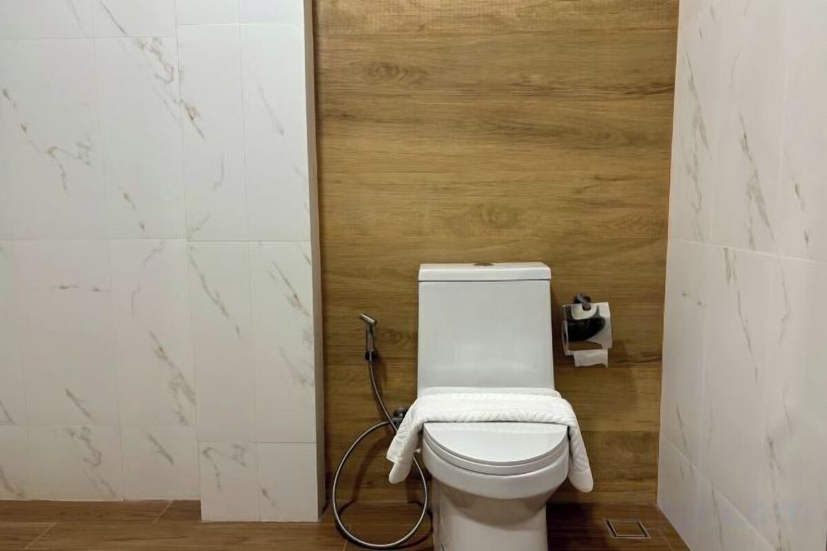 A bathroom with a toilet, a shower, and a wooden wall.