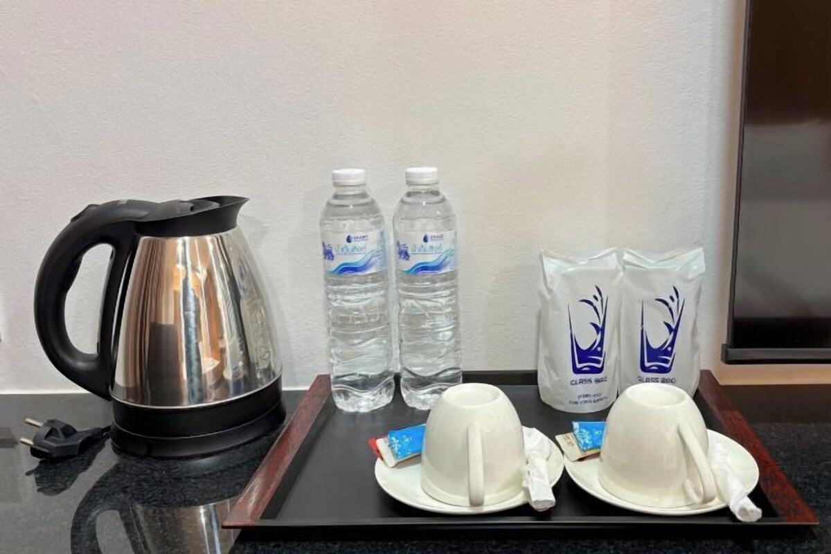 A tray with a kettle, two water bottles, two white cups, and two white teacups on a black tray.