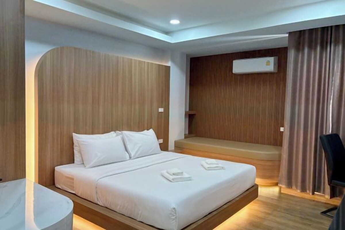 A modern hotel room with a bed, a desk, and a chair.