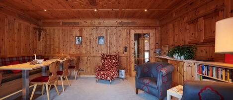 A wooden interior with a dining area, a sofa, and a bookshelf.