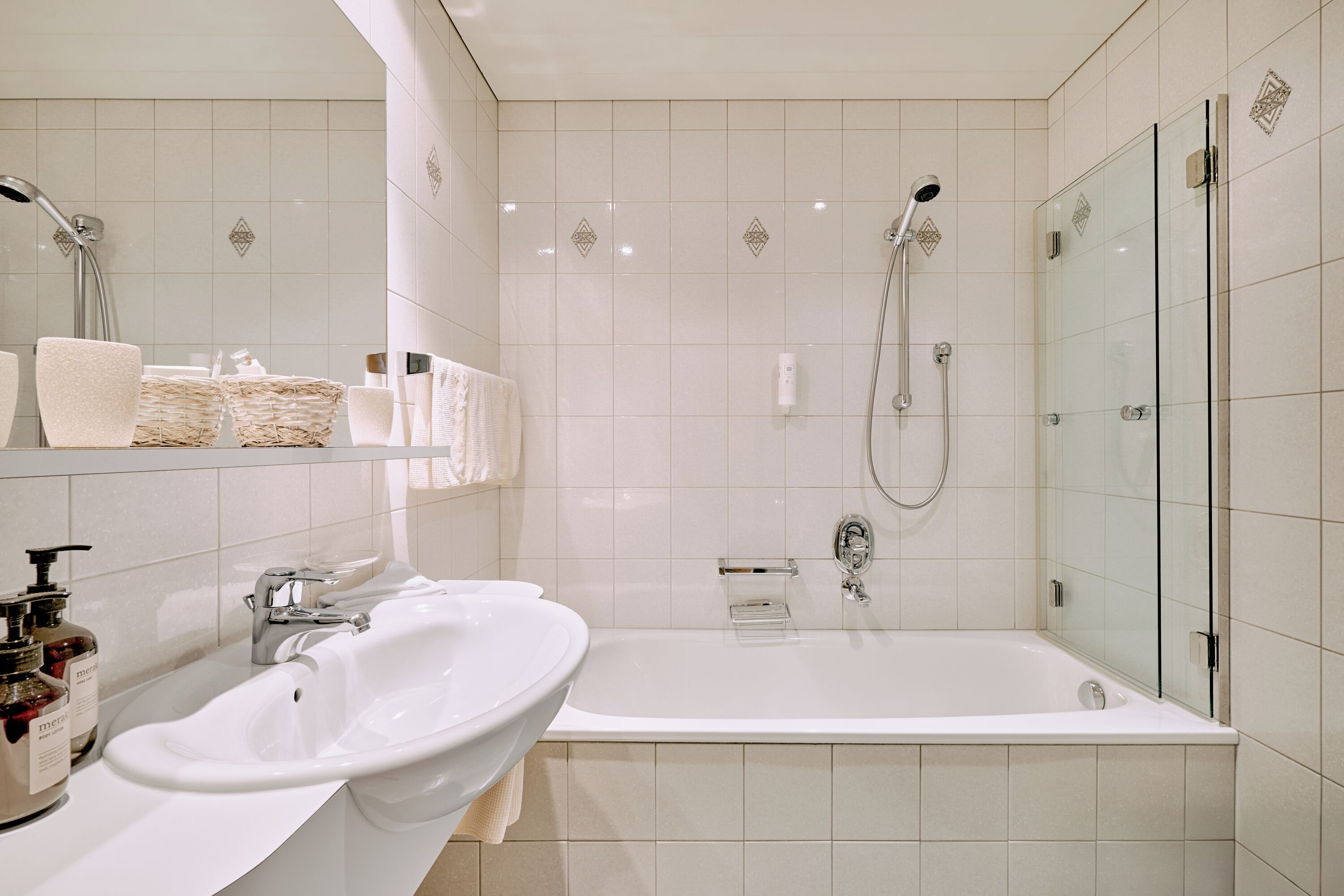 Une salle de bain moderne dotée d’une grande baignoire, de deux lavabos et d’une douche à parois de verre.