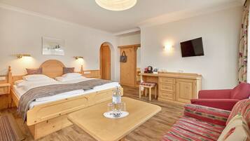 Ein Hotelzimmer mit Bett, Schreibtisch, Fernseher und einer Couch.