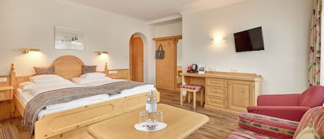 Una habitación de hotel con cama, escritorio, televisor y sofá.