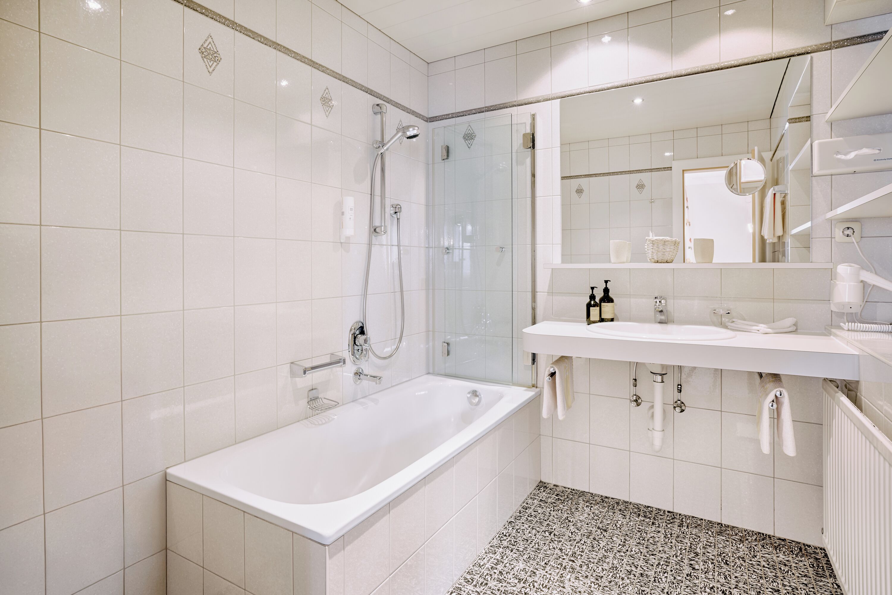 A modern bathroom with a bathtub, shower, and sink.