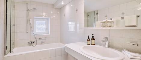 A modern bathroom with a bathtub, a sink, and a glass shower enclosure.