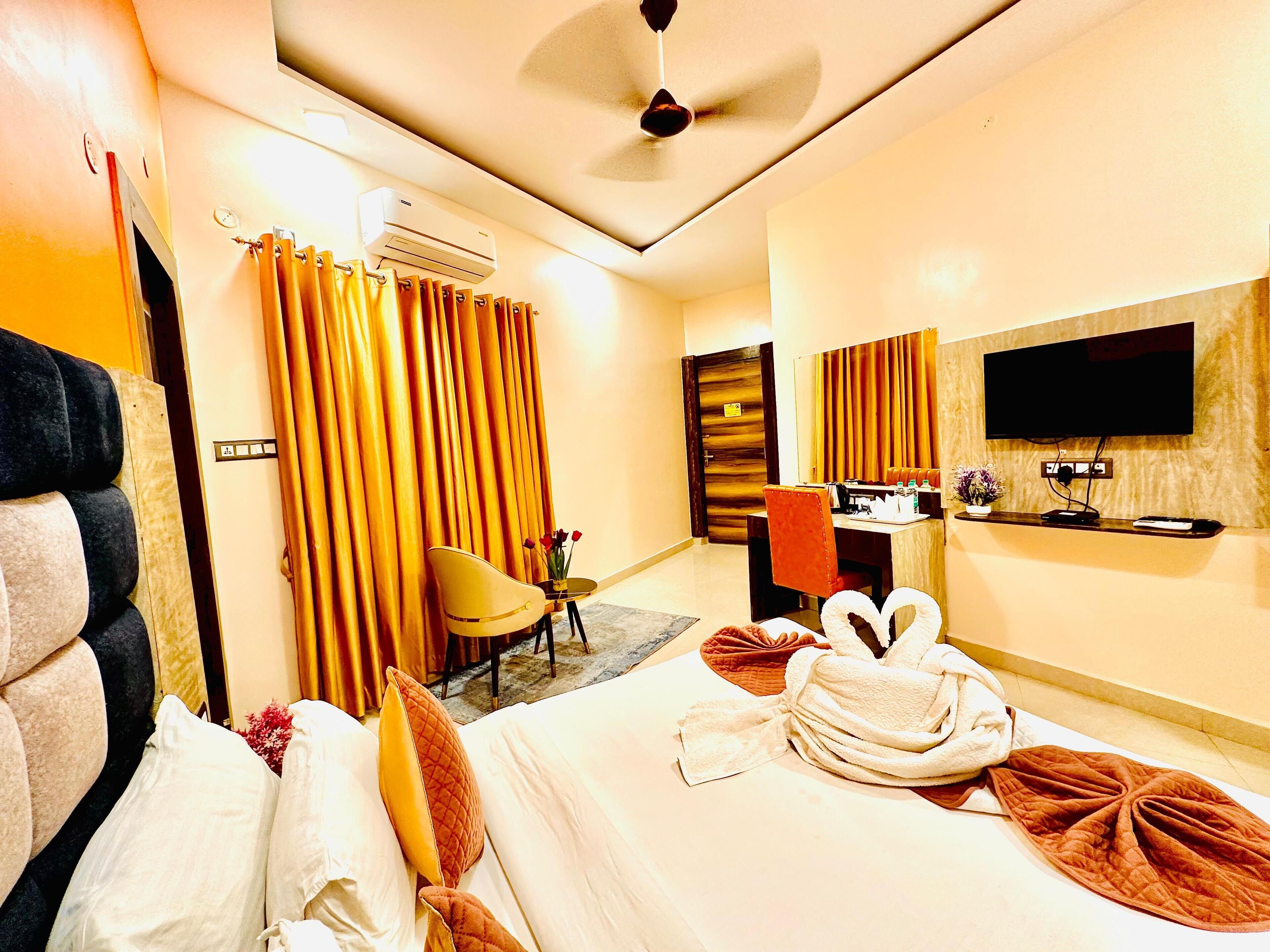 A hotel room with a bed, a desk with a chair, a TV, and an air conditioning unit.