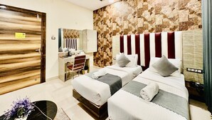 Quarto de hotel com duas camas, uma toucador com espelho e parede com padrão geométrico.