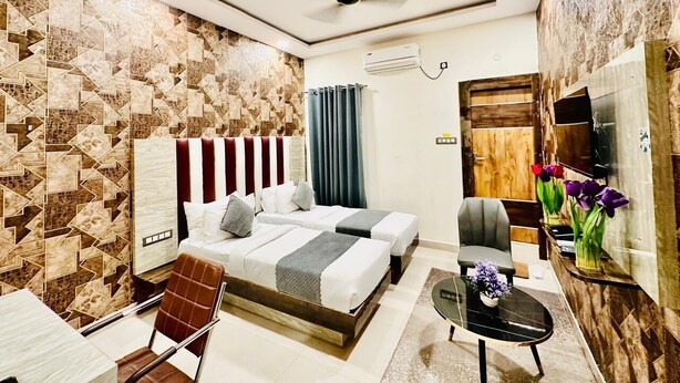 Quarto de hotel com cama, cadeira, mesa pequena e televisão.