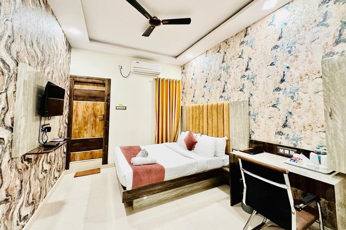 Een hotelkamer met een bed, bureau en plafondventilator.