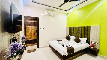 Una habitación de hotel moderna con una cama, un ventilador de techo, un televisor montado en la pared y una puerta de madera.