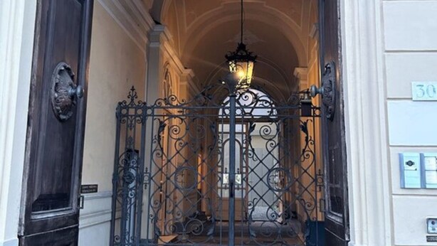 A grand entrance with a wrought iron gate, a chandelier, and a number sign indicating room 30.