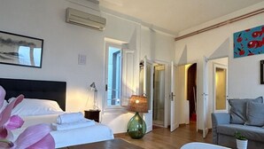 A hotel room with a bed, a lamp, a sofa, and a painting on the wall.