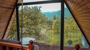A room with a sloped ceiling and large windows offering a view of a green landscape. - 3Gozel Qabala (Gabala)
