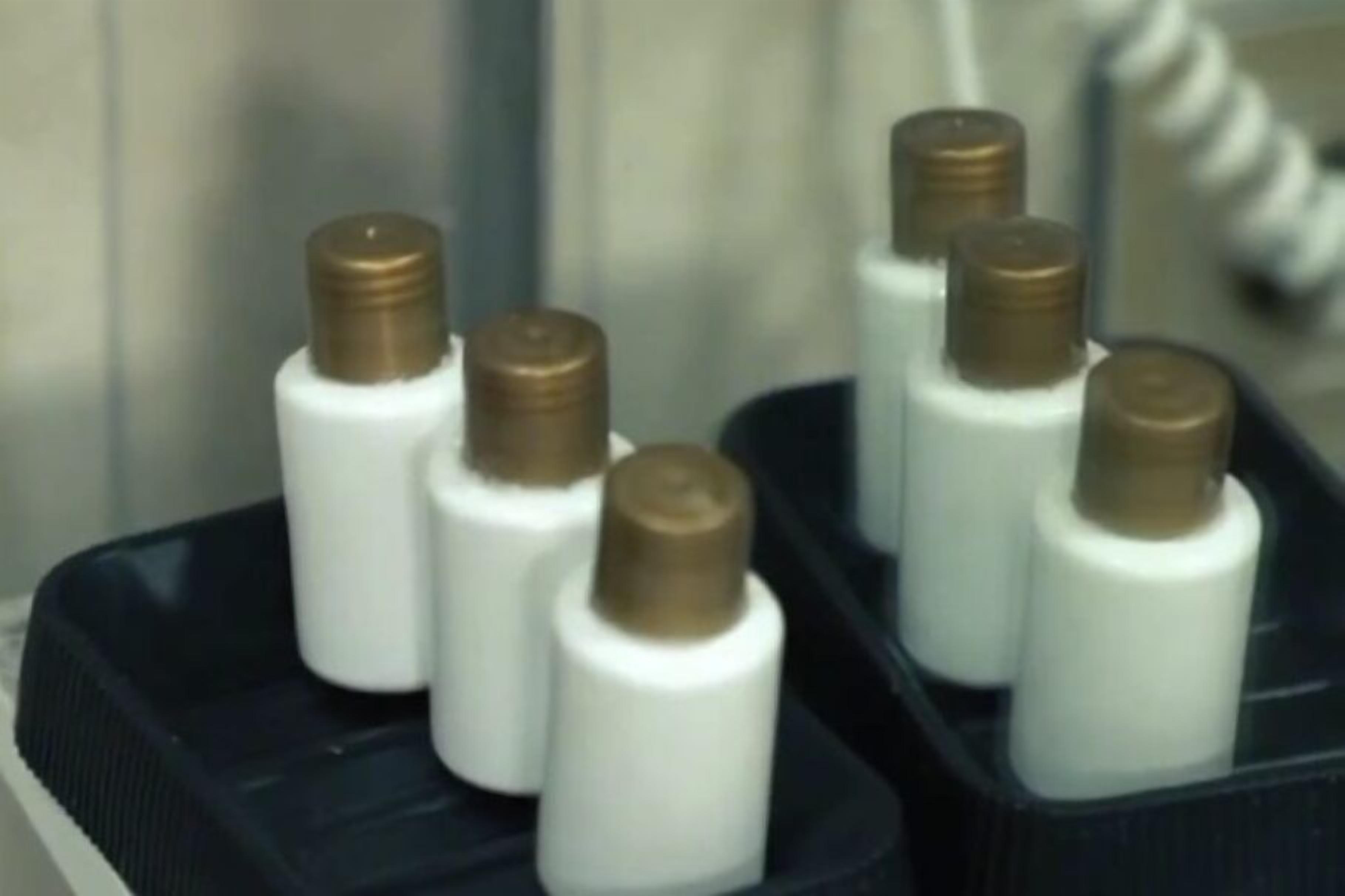 A tray with several white bottles with brown caps.