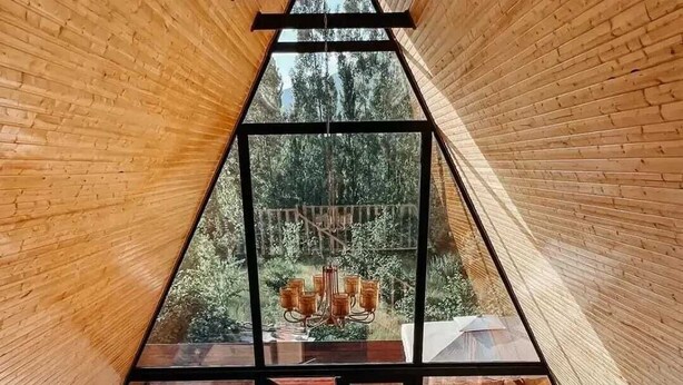 A triangular wooden interior with a glass ceiling, a wooden staircase, and a cushioned seating area. - 3Gozel Qabala (Gabala)