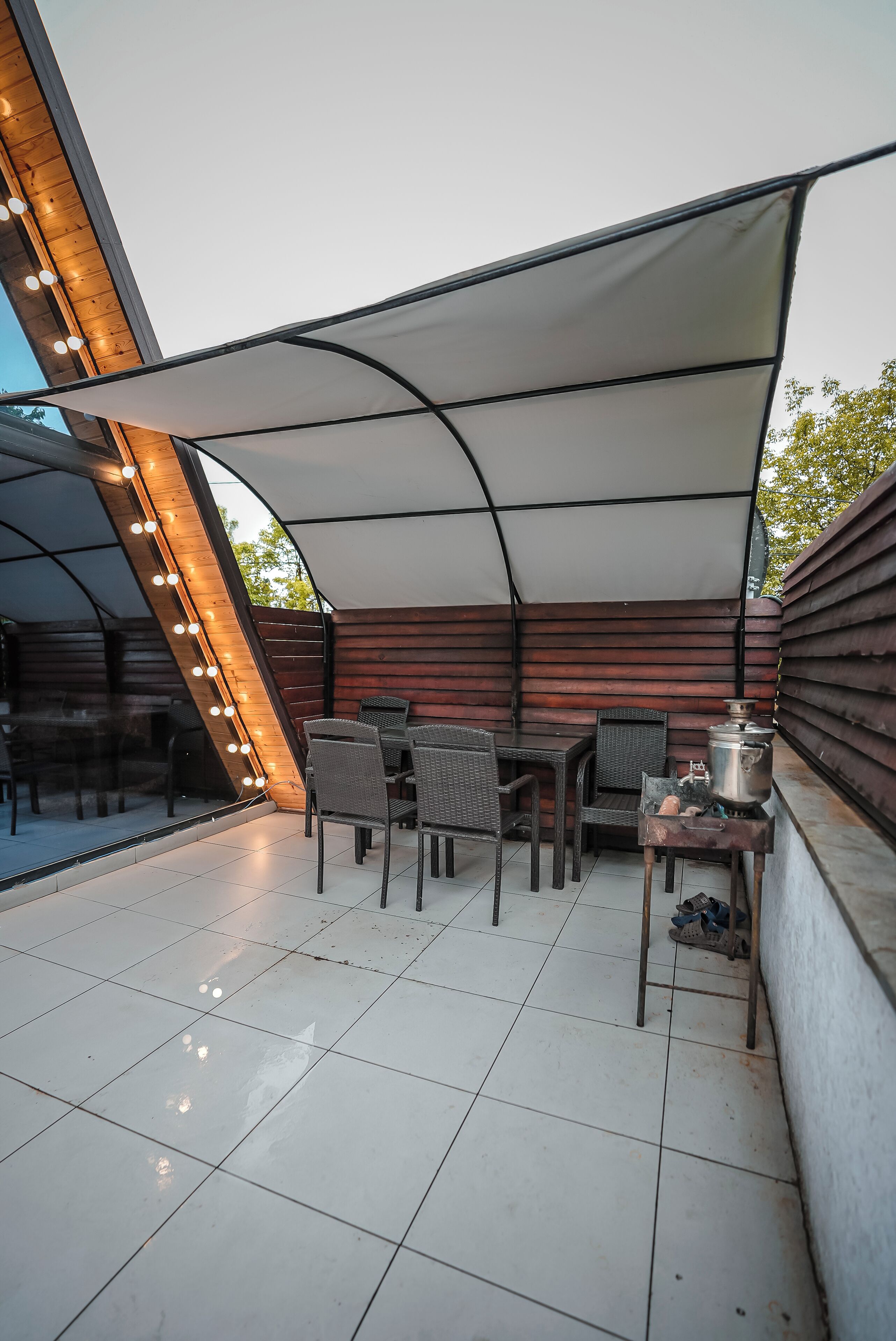 An outdoor patio with a covered seating area, a table with chairs, and a grill.