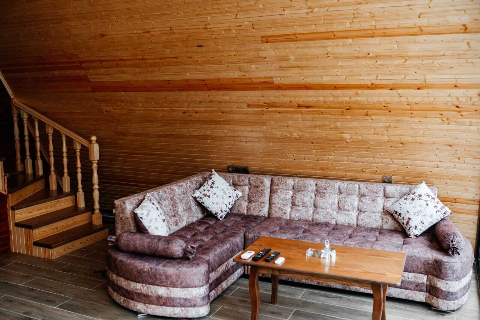 Ein Holzinnenraum mit einer gebogenen Couch, einem Holztisch und einer Treppe.