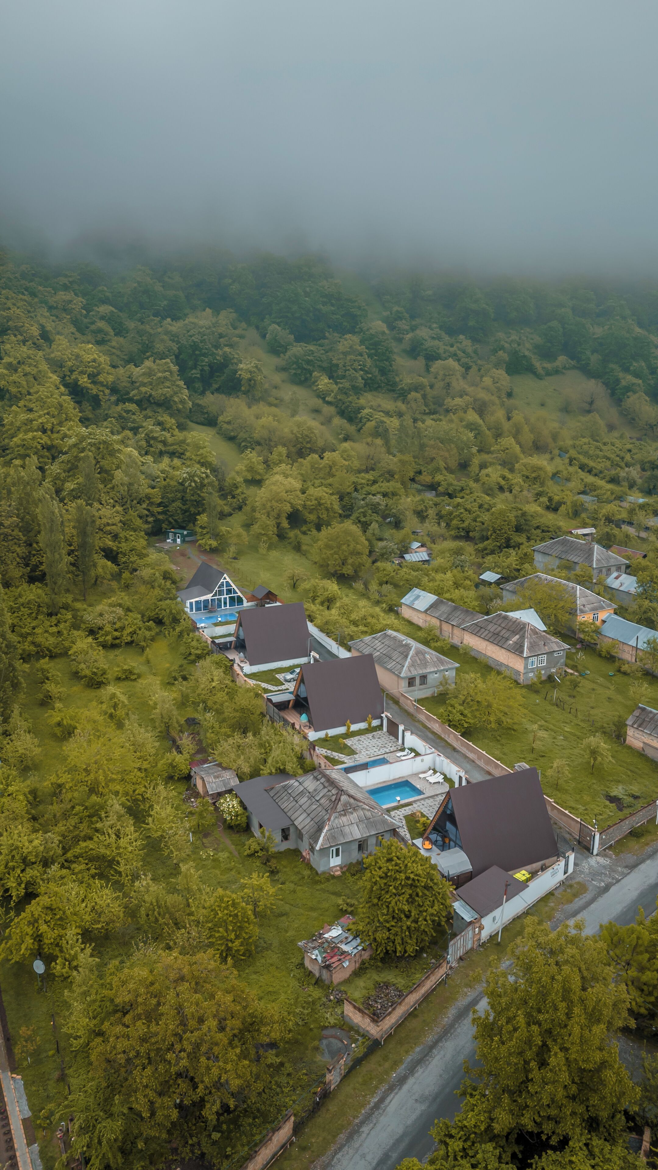 An aerial view of a residential area with houses, a swimming pool, and a road.