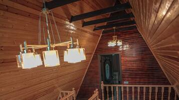 A wooden interior with a staircase, wooden beams, and hanging light fixtures.