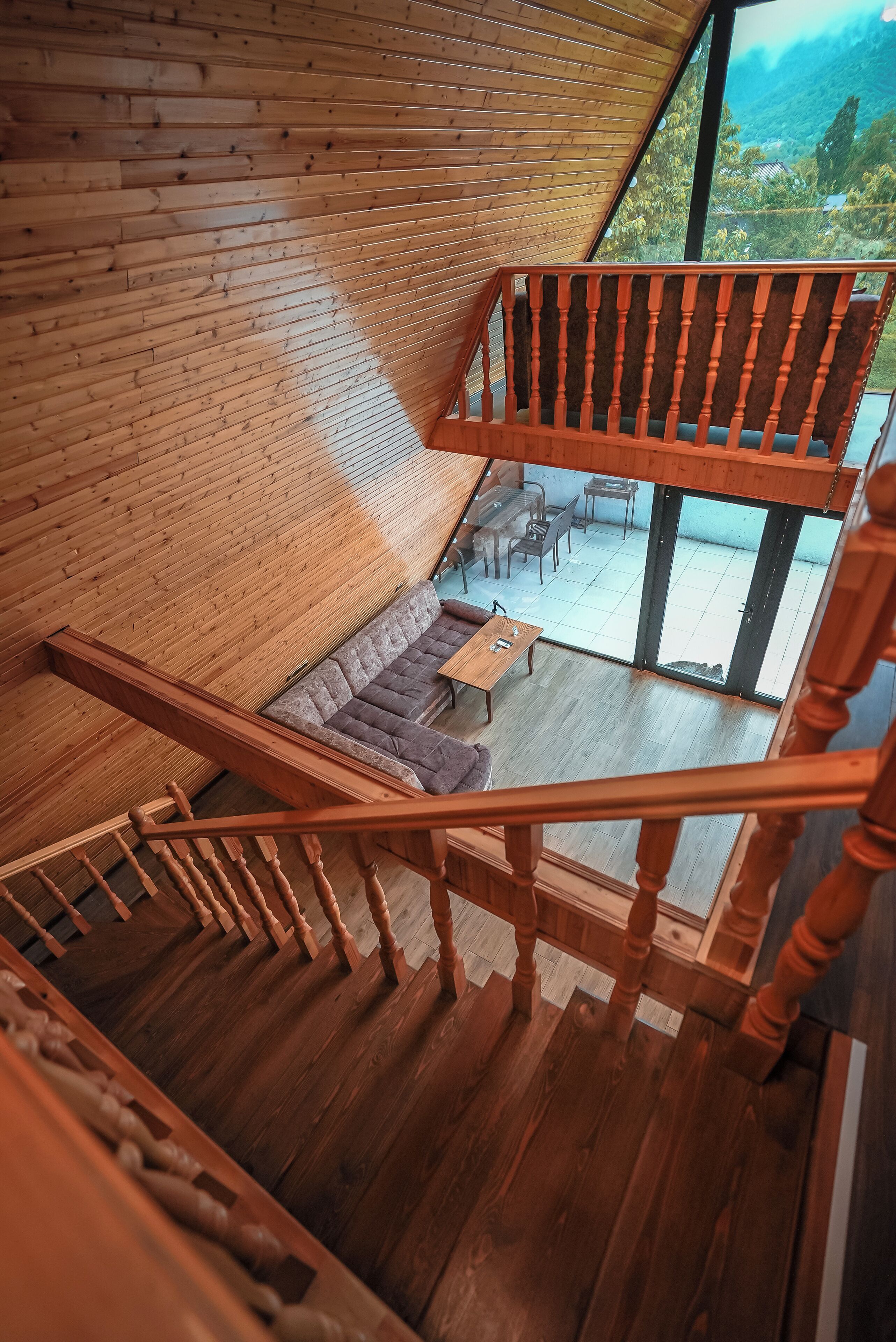 A wooden staircase leading to a balcony with a view of a lush landscape.