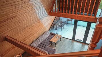 A wooden staircase leading to a balcony with a view of a lush landscape.