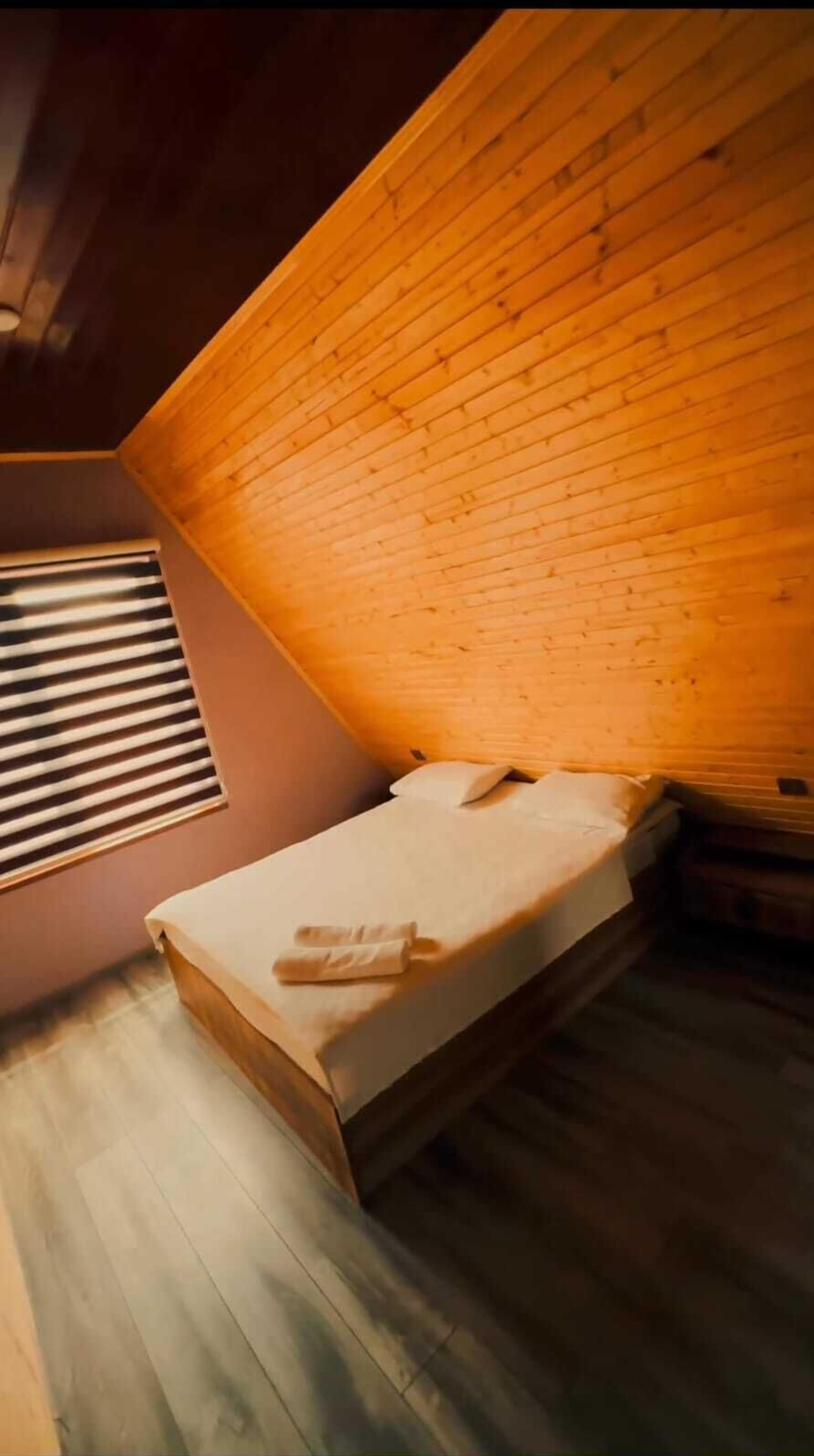 Um quarto pequeno e acolhedor com teto inclinado e uma cama de solteiro.